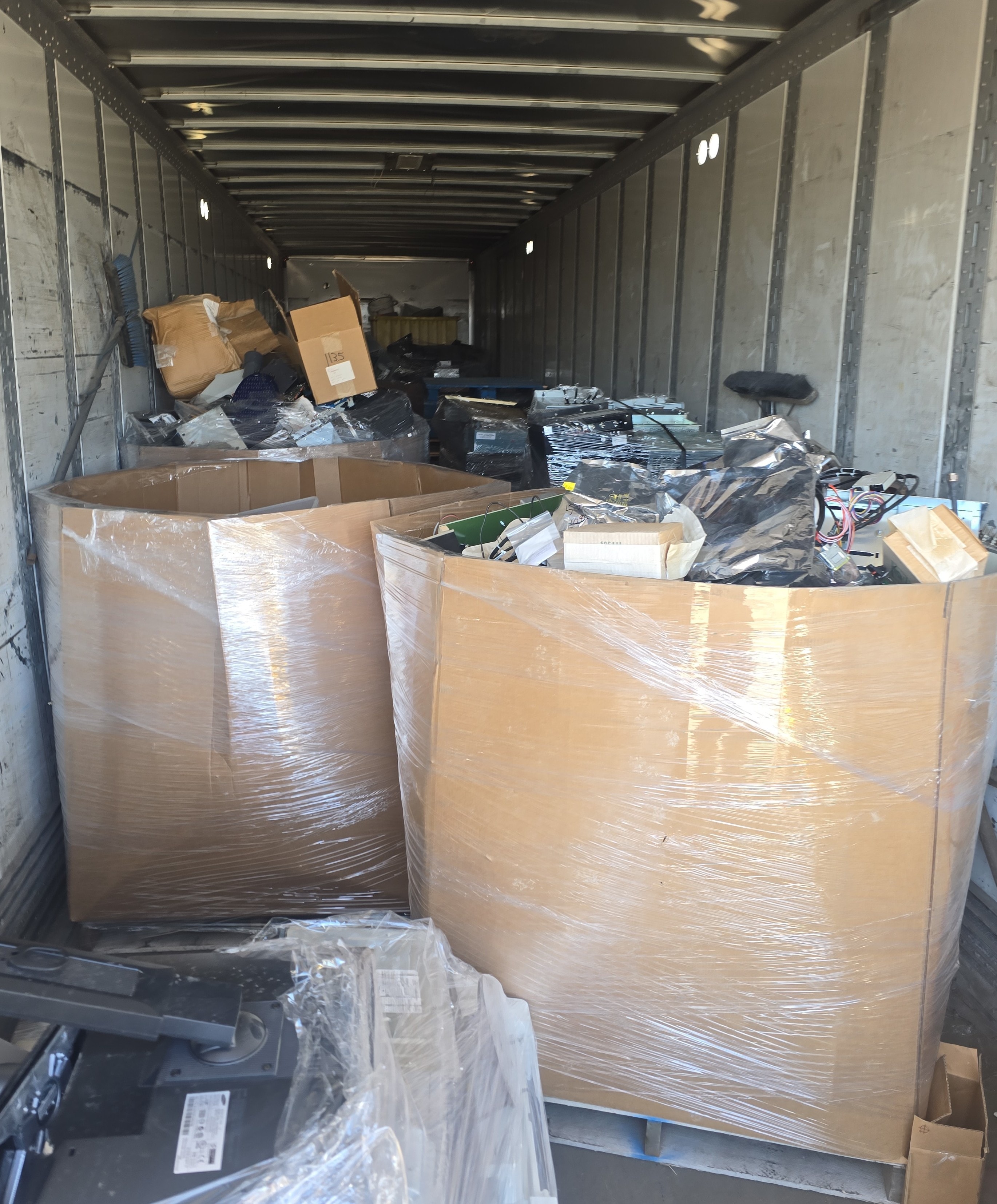 Packaged e-waste pallets secured in trailer for recycling transport