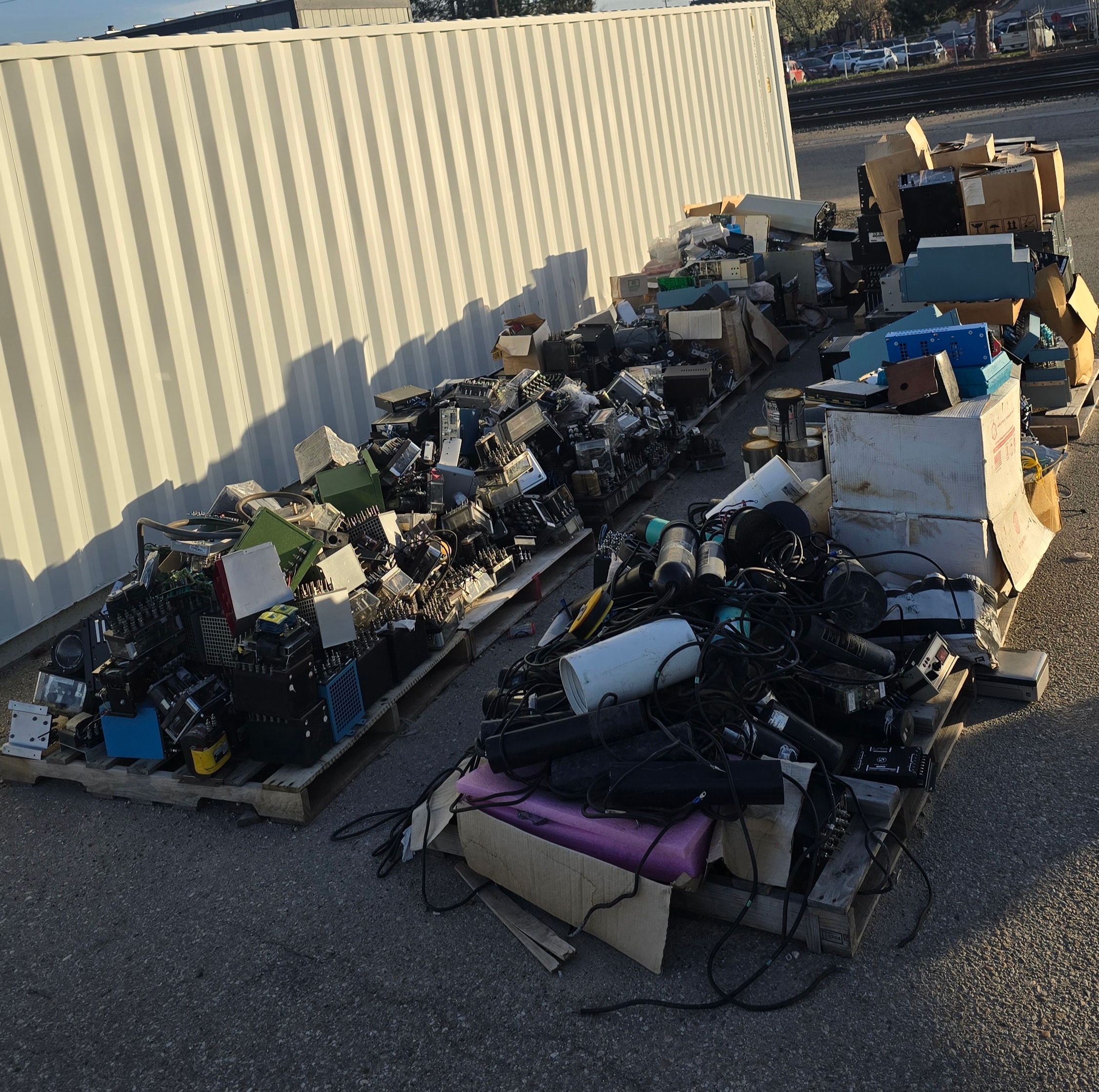 E-waste electronics piled on outdoor pallets before pickup